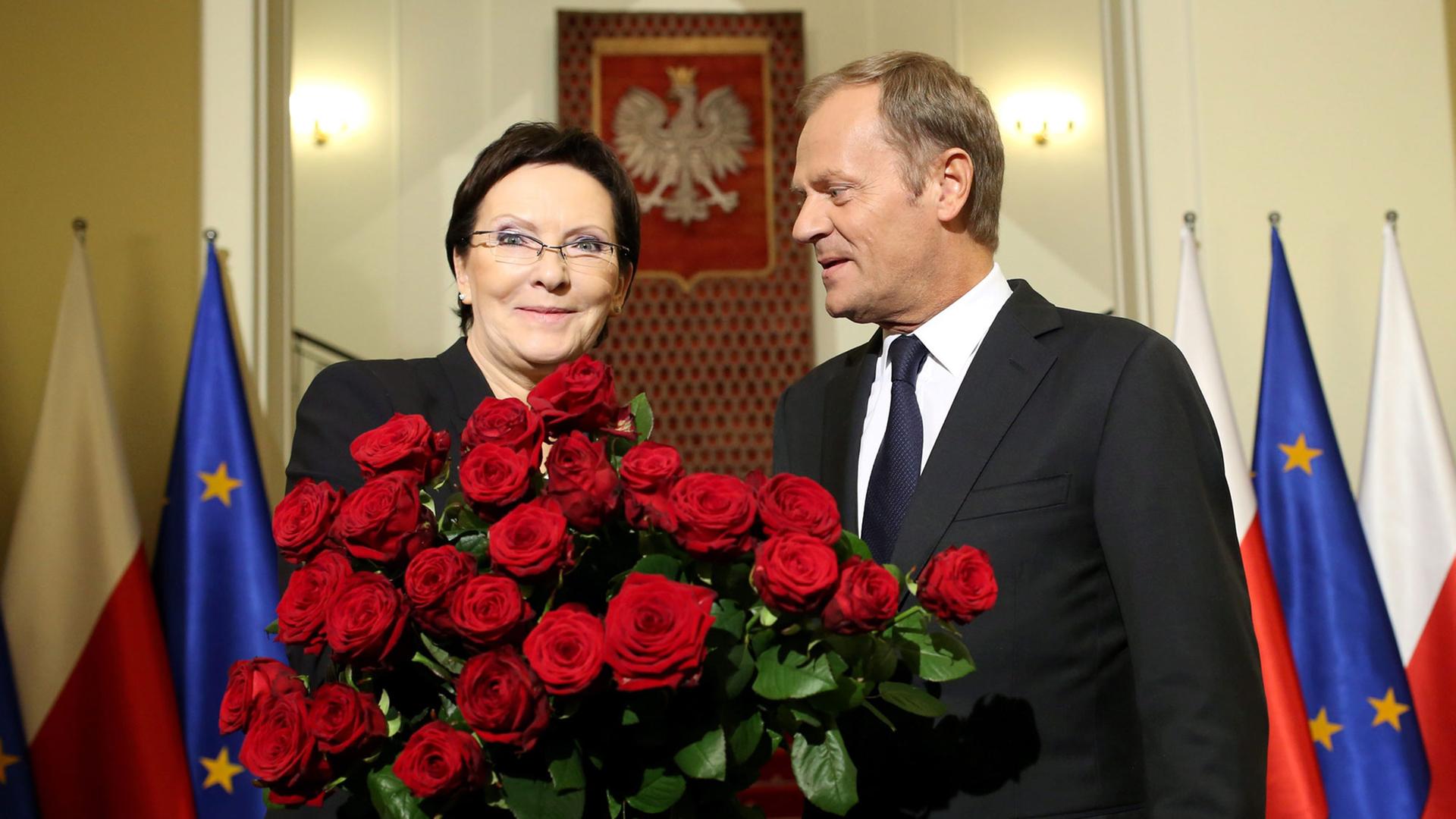 Der scheidende polnische Ministerpräsident Donald Tusk (r.) steht neben seiner Nachfolgerin Ewa Kopacz, die einen Rosenstrauß in den Händen hält.