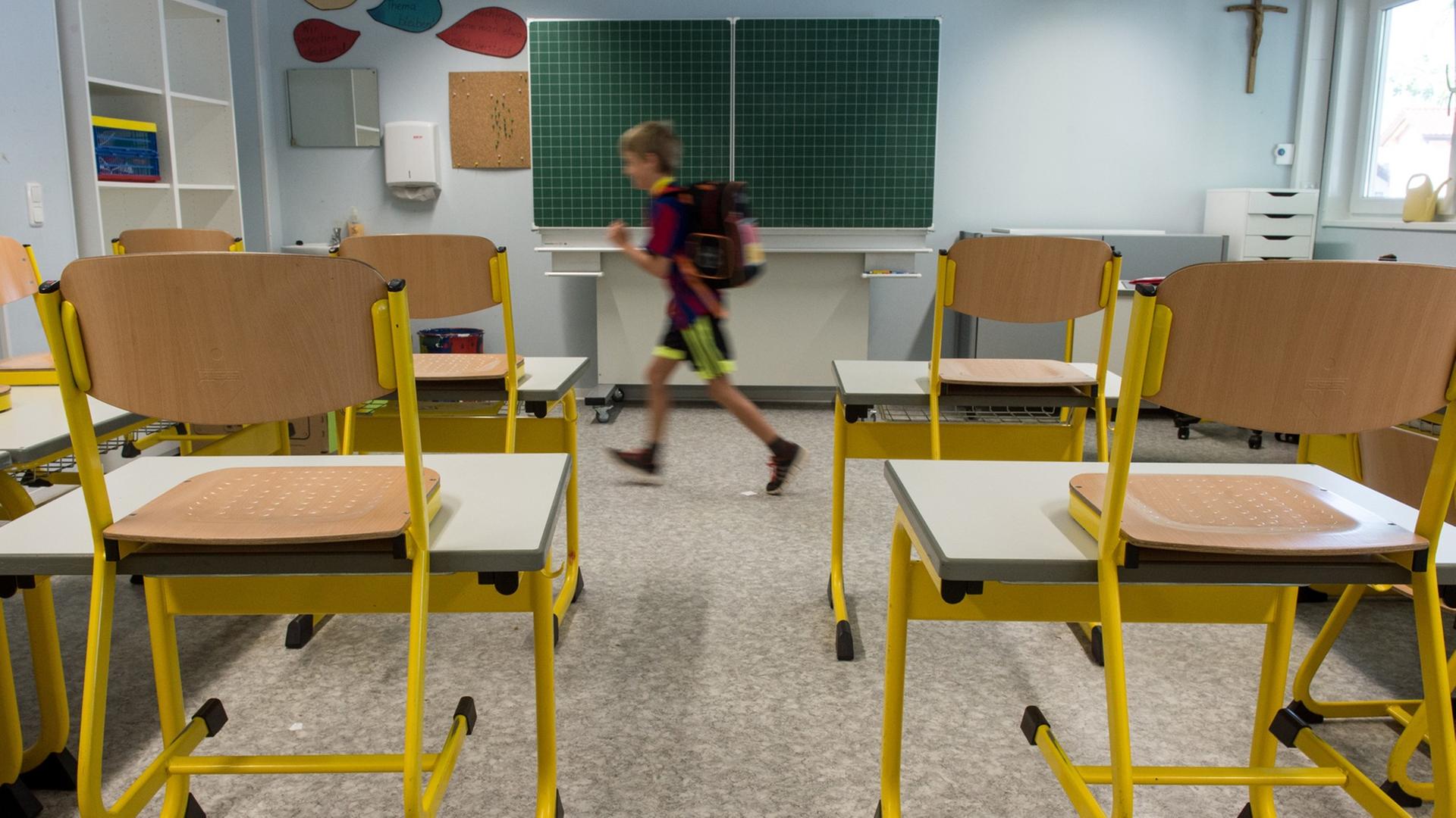 Leeres Klassenzimmer mit hochgestellten Stühlen, aus dem ein einzelner Schüler hinaus läuft.