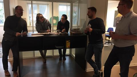 Um einen Tisch stehen vier Männer und eine Frau und halten eine Redaktionskonferenz ab. Sie sind Teil der Lokalzeitung Nordschleswiger.