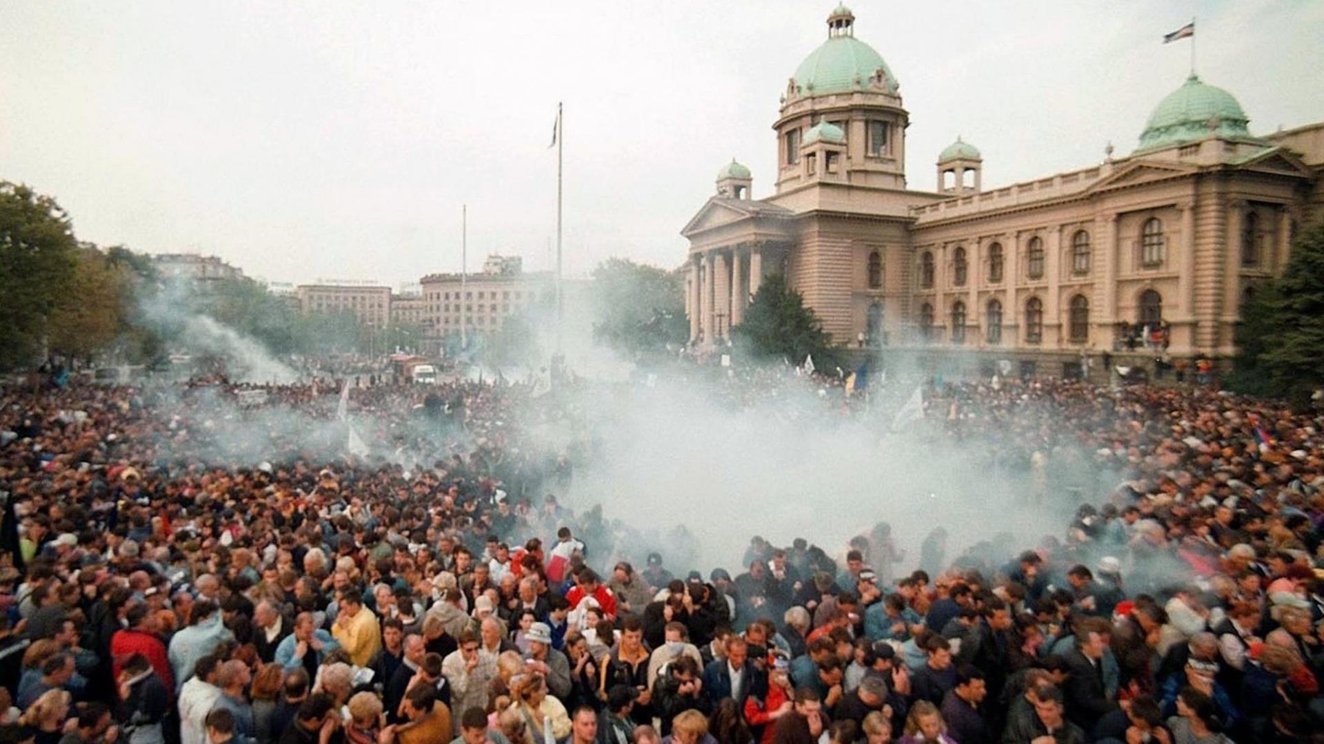 Rauchschwaden über einergroßen Menschenmenge Hunderttausende Anhänger der serbischen Opposition versammelten sich am 5.10.2000 vor dem Parlamentsgebäude in Belgrad Über ihnen steht eine Tränengaswolke, die von Patronen der Polizei ausgelöst wurde. Nach dem Aufstand gegen Jugoslawiens Präsidenten Milosevic ist die Opposition zur Machtübernahme bereit. Der bei den Präsidentschaftswahlen siegreiche Kostunica kündigte im serbischen Fernsehen am späten Donnerstagabend (5.10.) an, rasch die Amtsgeschäfte übernehmen zu wollen.