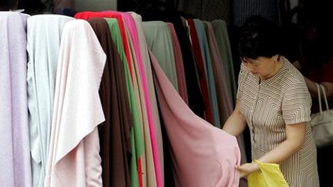 Eine Chinesin begutachtet Textilien auf einem Markt in Schanghai.