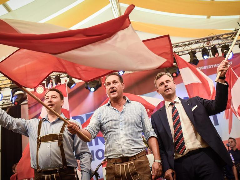FPÖ-Kandidat Hofer (r.), Parteichef Strache (M.) und der Landeshauptmann-Stellvertreter Oberösterreichs, Haimbuchner (l.), schenken auf der FPÖ-Auftaktveranstaltung zum Wahkampf der wiederholten Präsidentenwahl Fahnen.