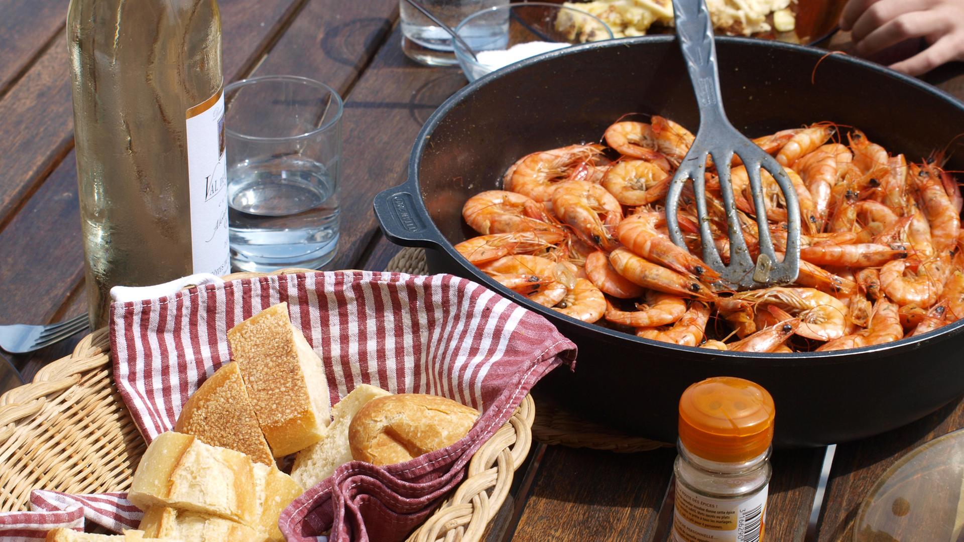Blick auf eine Tisch mit einer Pfanne Gambas, Weißbrot und Wein Blick auf eine Tisch mit einer Pfanne Gambas, Weißbrot und Wein