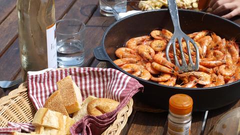 Blick auf eine Tisch mit einer Pfanne Gambas, Weißbrot und Wein