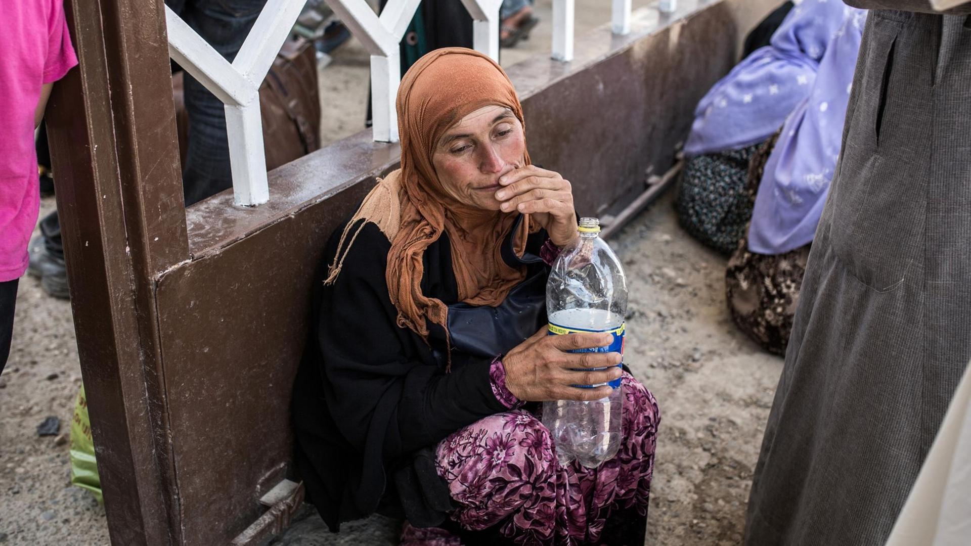 Eine Syrerin trinkt Wasser aus einer Flasche.