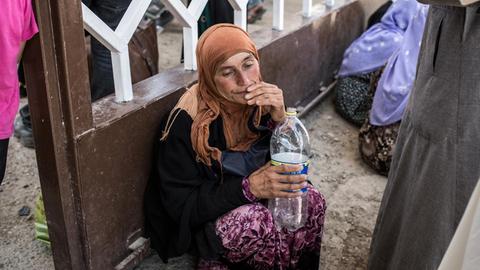 Eine Syrerin trinkt Wasser aus einer Flasche.