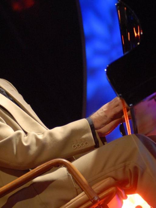 Der Liedermacher Rainald Grebe auf der Bühne am Klavier bei einem Konzert.