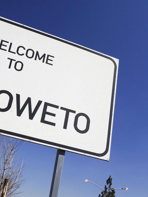 Straßenschild vor blauem Himmel, auf dem "Welcome to Soweto" – Herzlich Willkommen in Soweto – steht