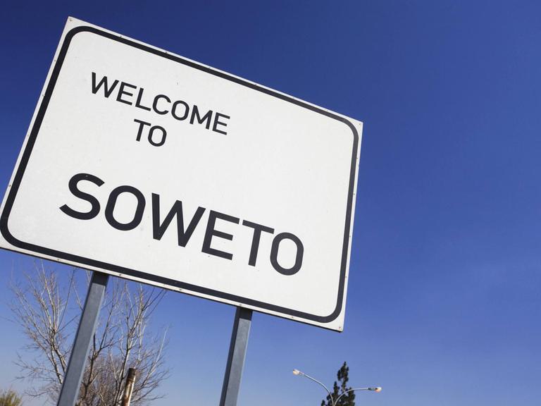 Straßenschild vor blauem Himmel, auf dem "Welcome to Soweto" – Herzlich Willkommen in Soweto – steht