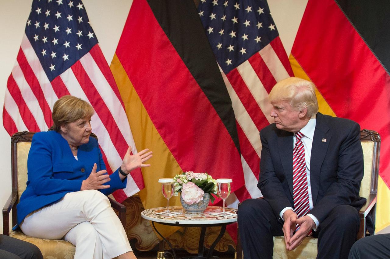 Das Bild zeigt Bundeskanzlerin Angela Merkel und US-Präsident Donald Trump. Sei sprechen am 26.05.2017 während des G7-Gipfeltreffens in Taormina auf Sizilien (Italien). Sie sitzen vor deutschen und amerikanischen Flaggen an einem Tisch und schauen sich ernt an. 