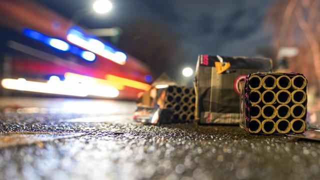 Zu sehen sind im Vordergrund Silvester-Böller, im Hintergrund verschwommen ein Feuerwehrfahrzeug.