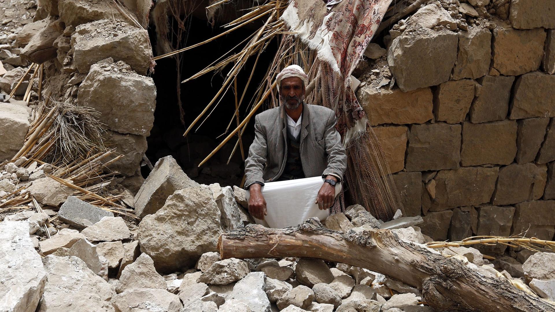 Ein Mann im Jemen sitzt neben seinem zertrümmerten Haus, das durch einen Luftangriff der von Saudi-Arabien geführten Militärallianz zerstört wurde.