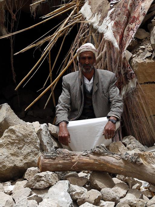 Ein Mann im Jemen sitzt neben seinem zertrümmerten Haus, das durch einen Luftangriff der von Saudi-Arabien geführten Militärallianz zerstört wurde.