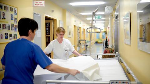 Zwei Pflegerinnen bereiten ein frisches Bett vor