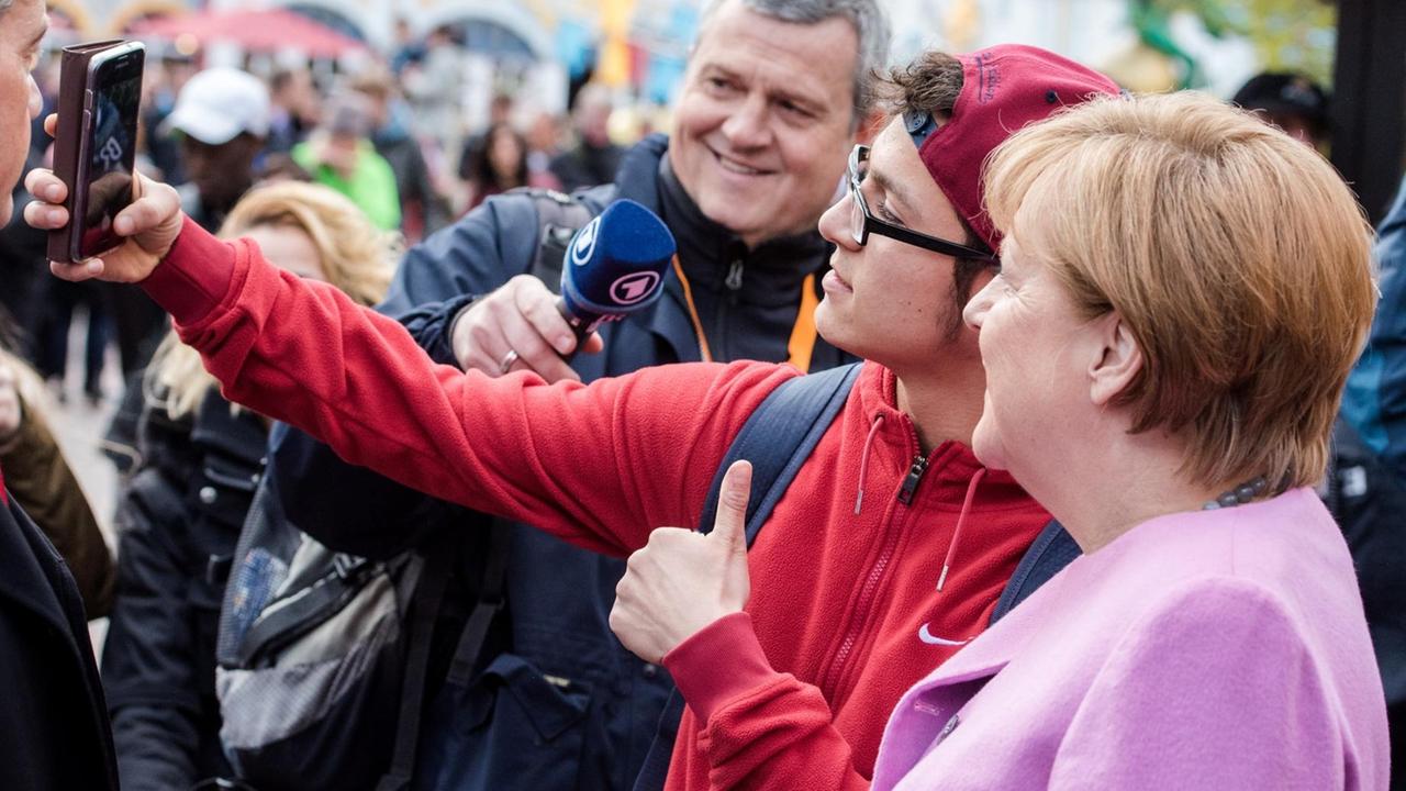 Bundeskanzlerin Angela Merkel (CDU) macht am 28.04.2017 in Sierksdorf (Schleswig-Holstein) während eines Wahlkampfauftrittes der CDU im Hansa Park mit einem Parkbesucher ein Selfie.