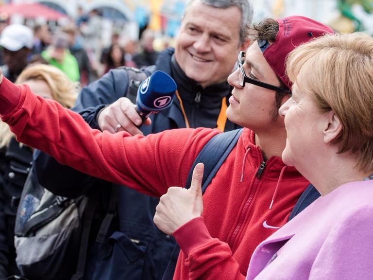 Bundeskanzlerin Angela Merkel (CDU) macht am 28.04.2017 in Sierksdorf (Schleswig-Holstein) während eines Wahlkampfauftrittes der CDU im Hansa Park mit einem Parkbesucher ein Selfie.