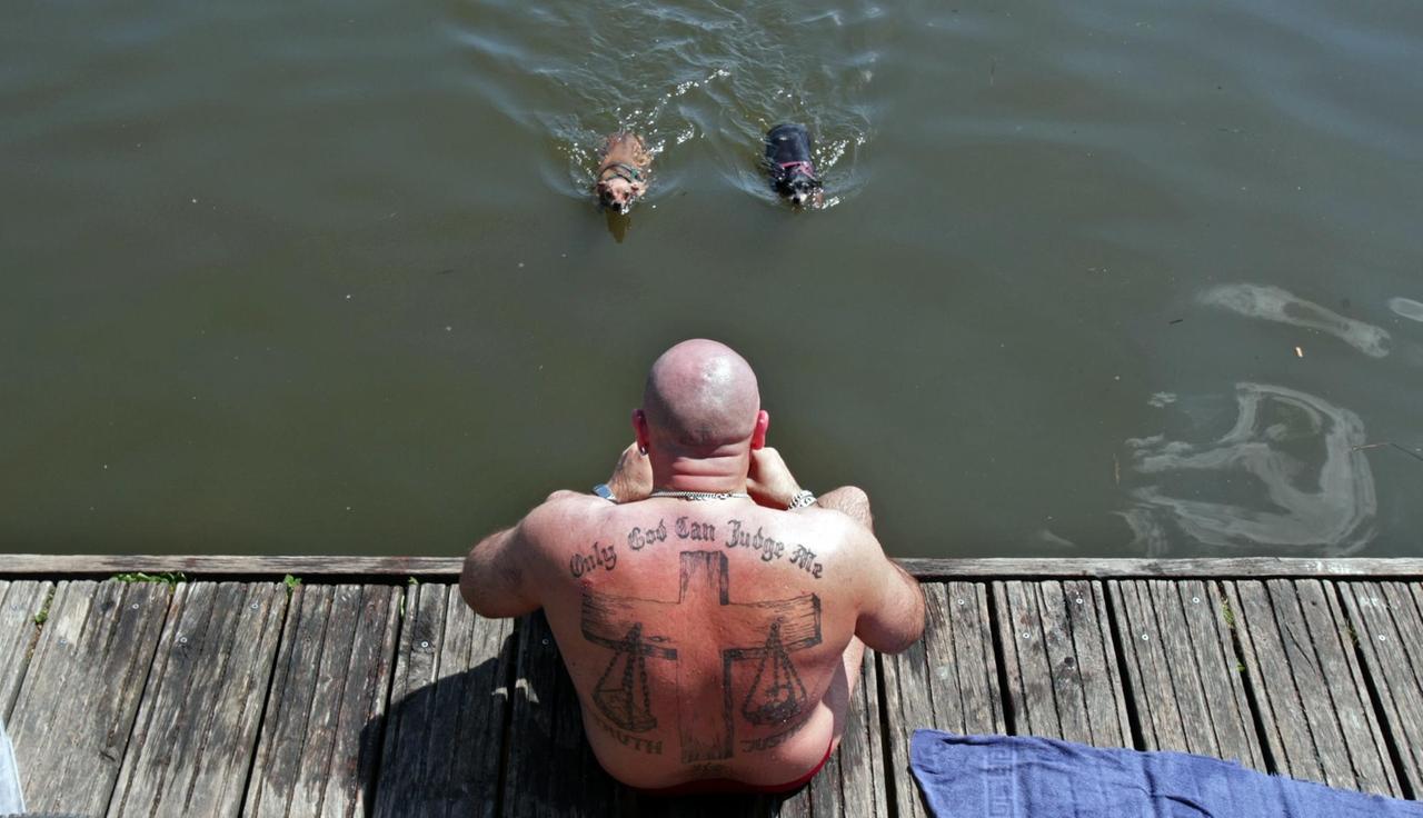 Ein Badegast in Hamburg mit einem Tattoo mit einer religiösen Aufschrift und Symbolik