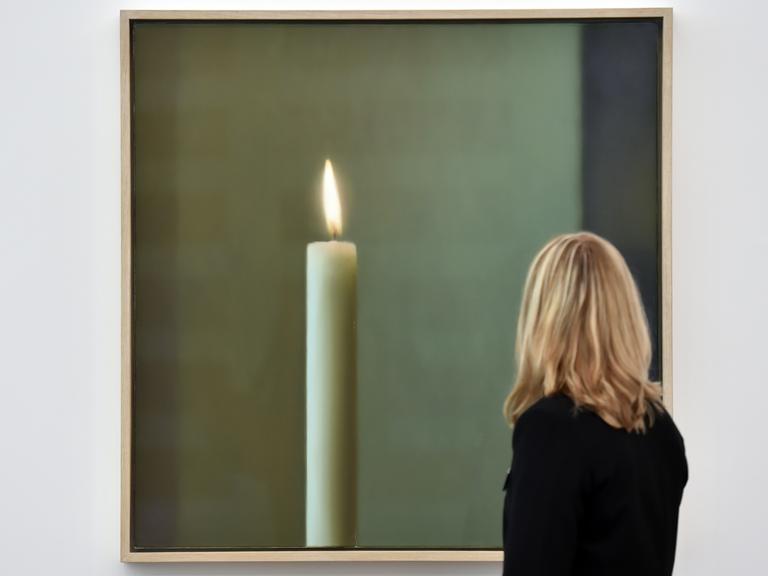 Eine Besucherin der Ausstellung betrachtet Gerhard Richters Werk "Kerze", ein Bild mit einer großen Kerze drauf, Frau ist nur von hinten zu sehen.