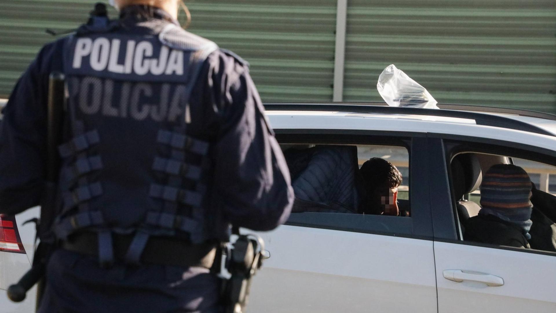 Ein Polizist steht am 3.10.2021 an der polnisch-belarussischen Grenze und kontrolliert PKW