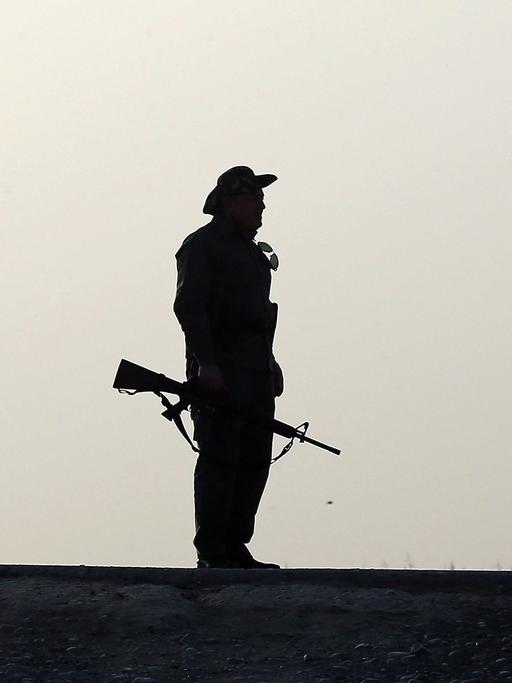 Ein Kämpfer der Peschmerga steht mit einer Waffe auf einer Straße