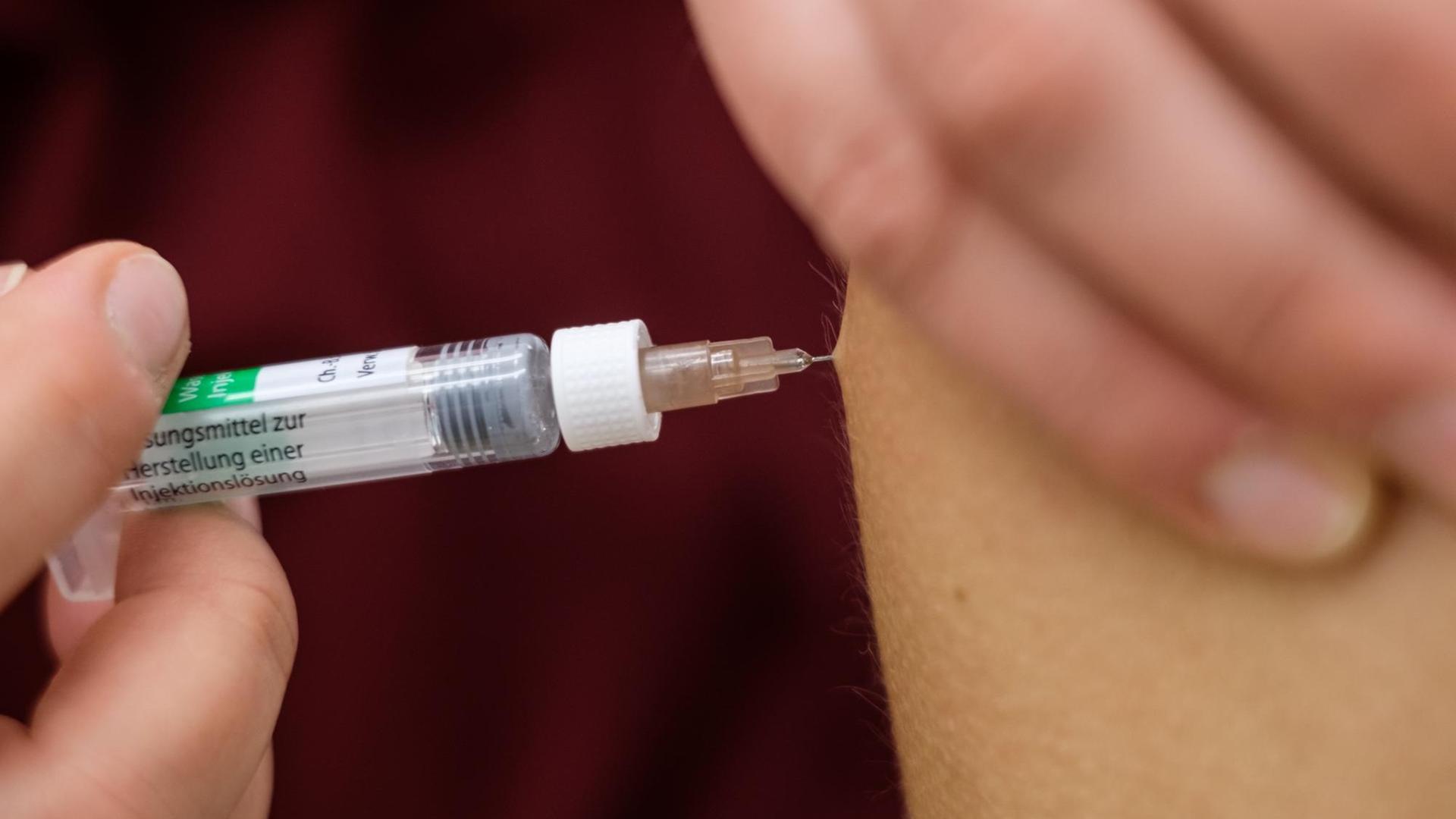 Eine Arzthelferin impft in einer Arztpraxis eine Patentin mit einer Spritze mit dem Impfstoff Rabipur zum Schutz vor Tollwut.