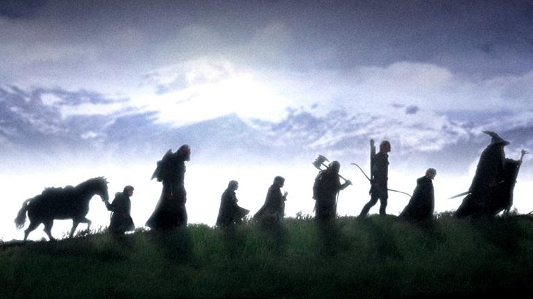 Filmszene aus "Herr der Ringe - Die Gefährten": Eine Gruppe von Wanderern ist als Schattenriss zu sehen.