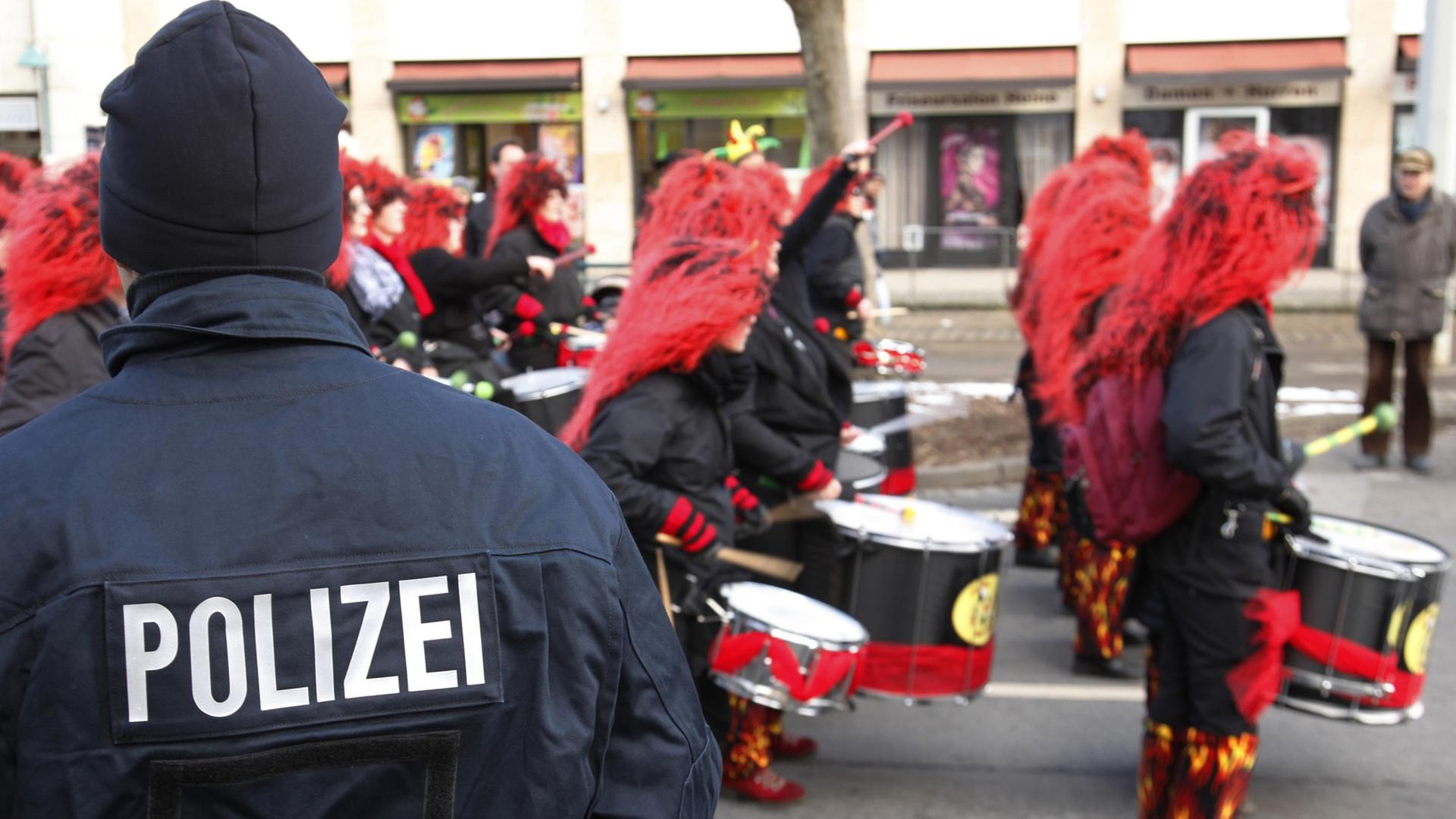 Ein Polizist steht beim Karnevalsumzug in Braunschweig, während verkleidete Narren an ihm vorbeiziehen, aufgenommen am 10.02.2013. Ein Polizist steht beim Karnevalsumzug in Braunschweig, während verkleidete Narren an ihm vorbeiziehen, aufgenommen am 10.02.2013.
