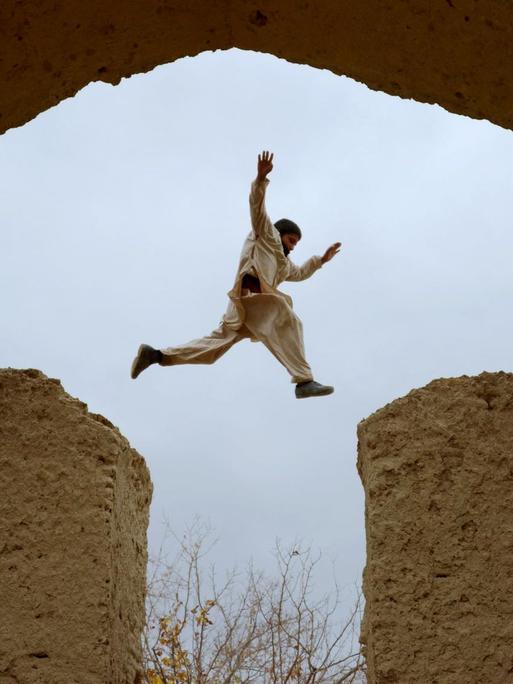 Ein afghanischer Junge springt in den Ruinen des Hauses, in dem der persische Poet Rumi im 13.Jahrhundert gelebt hat, Mazar-i-Sharif, Afghanistan.