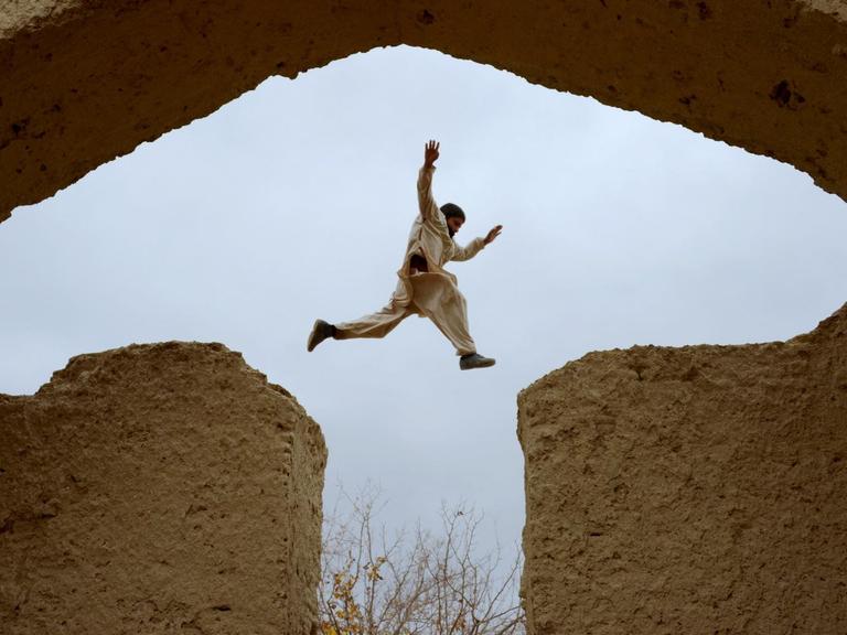Ein afghanischer Junge springt in den Ruinen des Hauses, in dem der persische Poet Rumi im 13.Jahrhundert gelebt hat, Mazar-i-Sharif, Afghanistan.