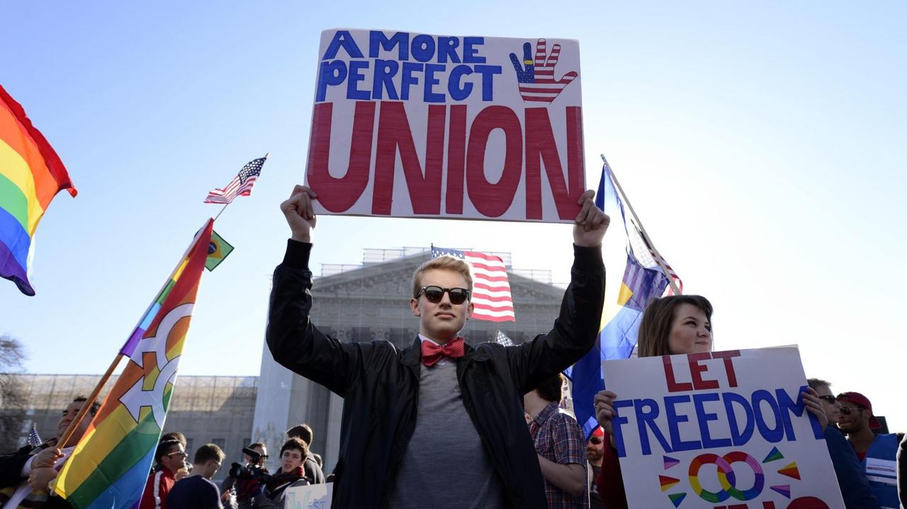 Ein Befürworter der gleichgeschlechtlichen Ehe hält bei einer Demo ein Banner mit der Aufschrift "A More Perfect Union" in die Luft.
