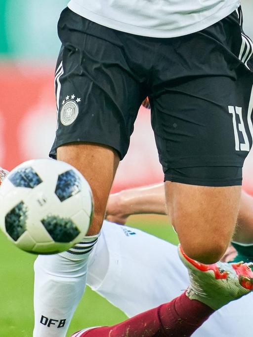 Ein deutscher U21-Spieler im Duell gegen einen mexikanischen Gegner, der am Boden liegt. Zu sehen sind nur die Beine der Spieler und der Ball.