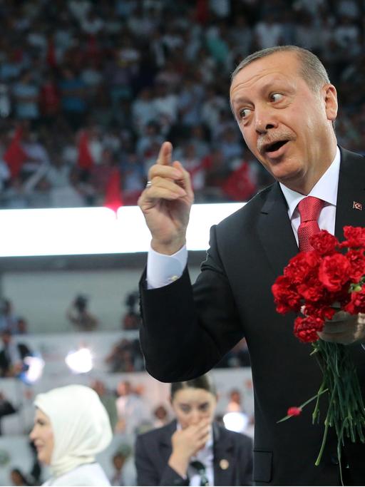 Recep Tayyip Erdogan wirft rote Blumen ins Publikum.