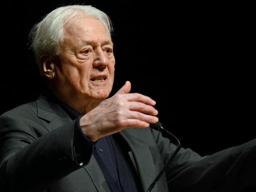 Porträt des Filmemachers und Schriftstellers Alexander Kluge, gestikulierend auf einer Bühne.