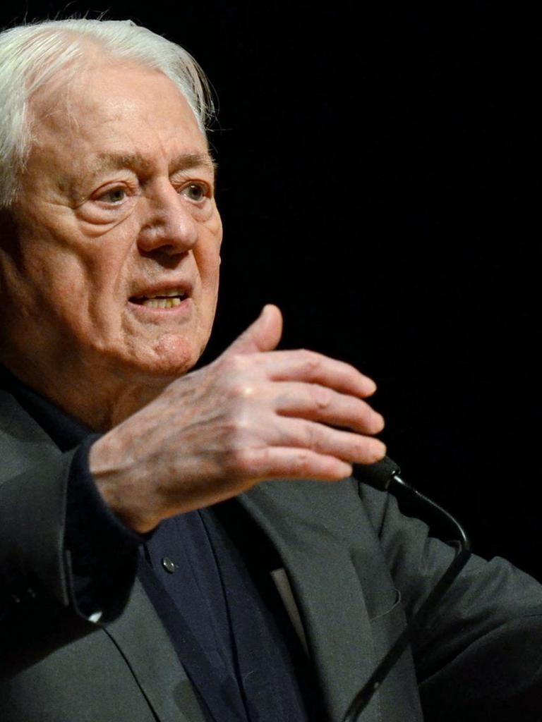 Porträt des Filmemachers und Schriftstellers Alexander Kluge, gestikulierend auf einer Bühne.