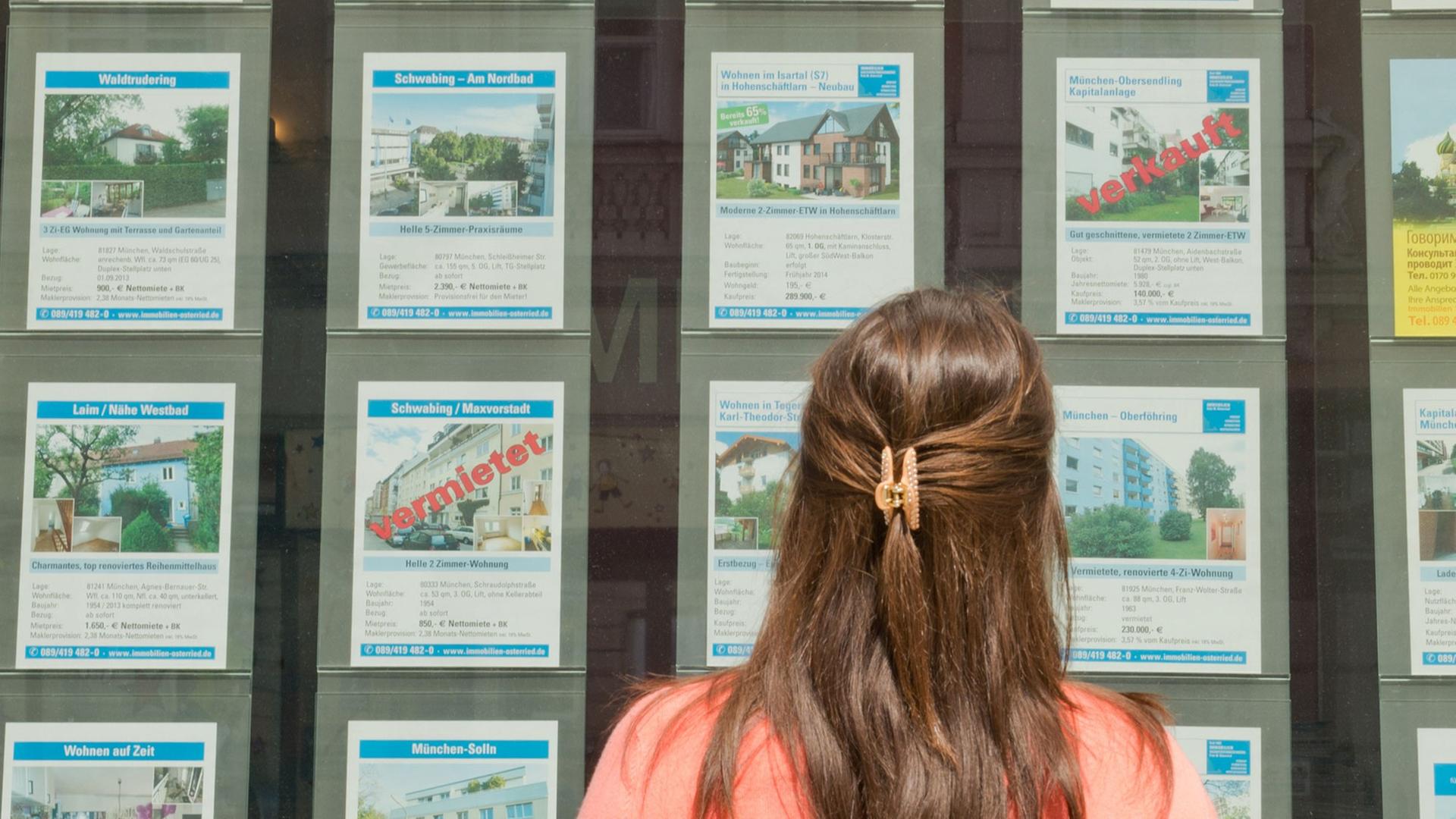 Ein Frau steht in München vor dem Büro eines Immobilienmaklers