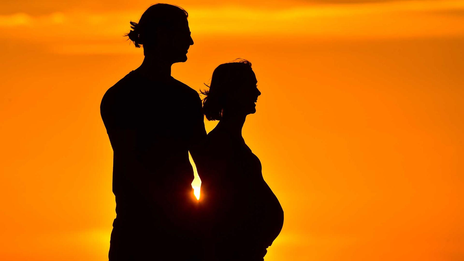 Zukünftige junge Eltern, eine im 8. Monat schwangere Frau und ihr Mann genießen zusammen den Sonnenuntergang, fotografiert am 09.08.2015 in Sieversdorf (Brandenburg).