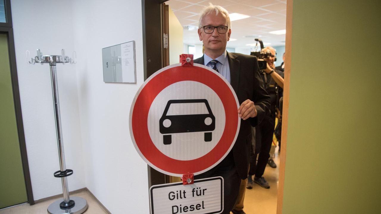 Jürgen Resch, Bundesgeschäftsführer der Deutschen Umwelthilfe geht nach der Urteilsverkündung im Stuttgarter Verwaltungsgericht mit einem Verkehrsschild aus dem Gerichtssaal.