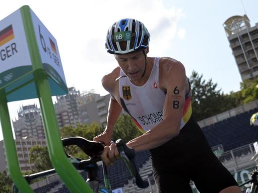 Der deutsche Triathlet Jonas Schomburg nimmt bei den Olympischen Spielen in Tokio in der Wechselzone sein Rennrad in Empfang.