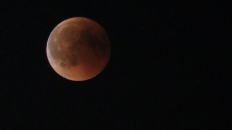 Der rot leuchtende Mond am schwarzen Himmel.