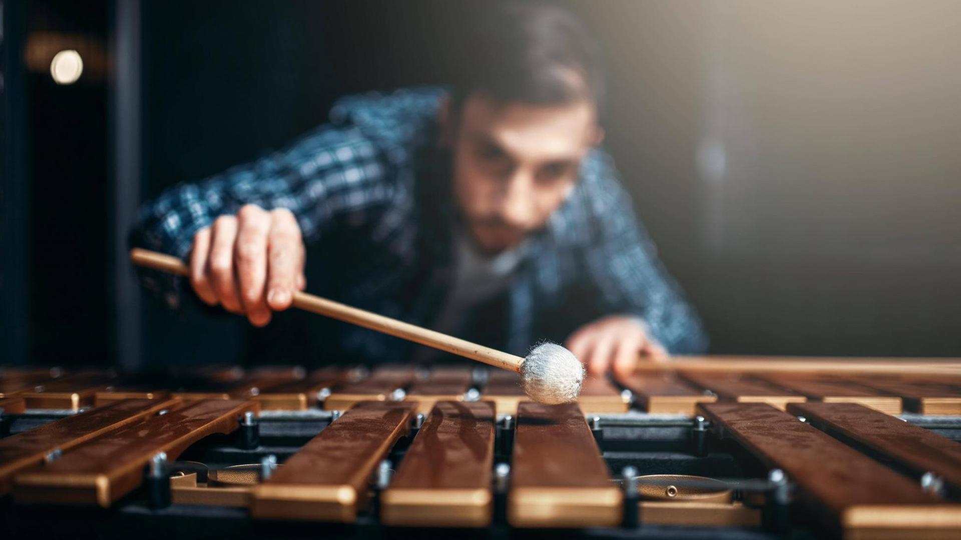 Ein Xylophon-Spieler beugt sich mit Schlägern über sein Instrument.