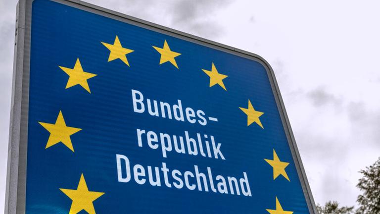 Ein Schild an der Grenze. Darauf steht: Bundesrepublik Deutschland. Das Schild ist blau und hat gelbe Sterne - wie die Fahne der Europäischen Union. Ein Schild an der Grenze. Darauf steht: Bundesrepublik Deutschland. Das Schild ist blau und hat gelbe Sterne - wie die Fahne der Europäischen Union.
