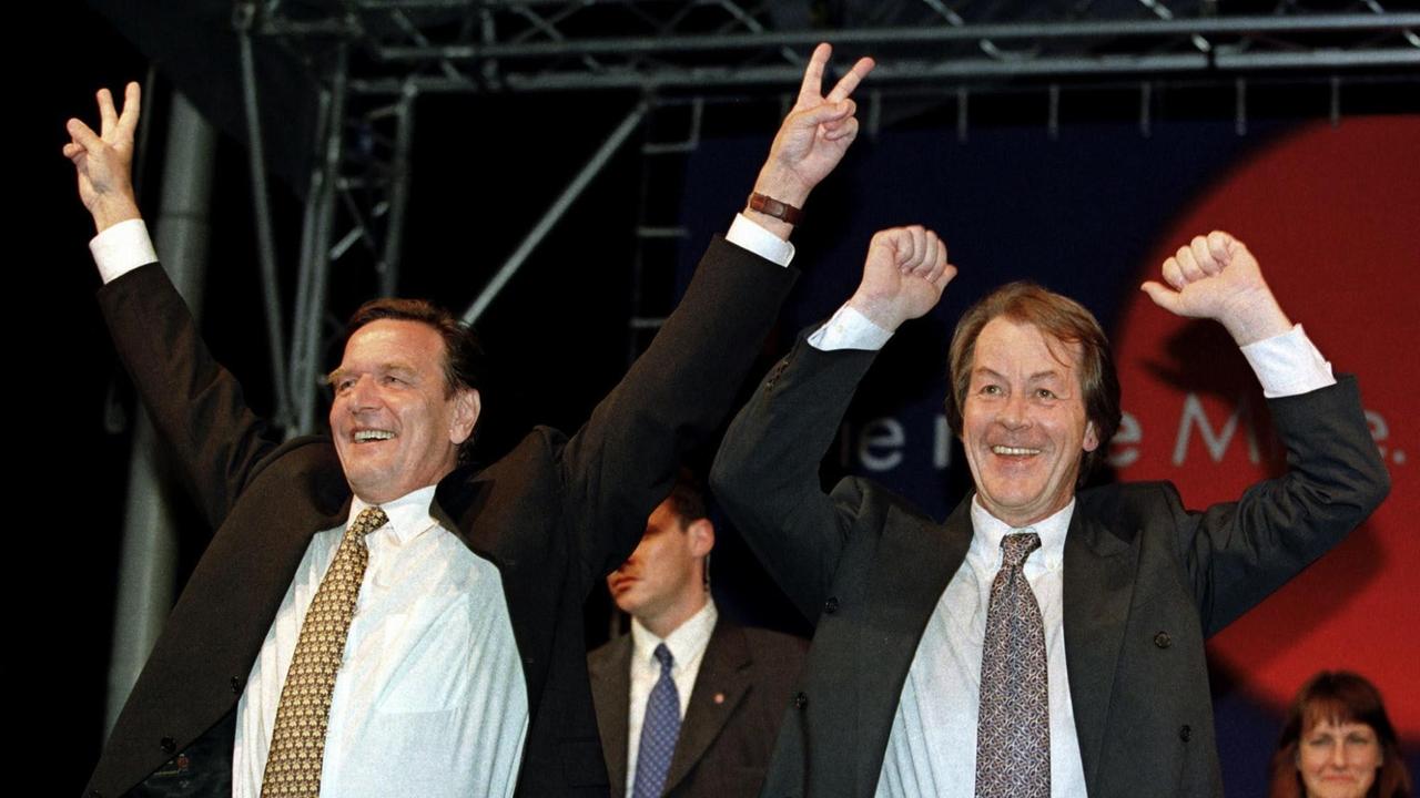 Gerhard Schröder (li.) und Franz Müntefering jubeln nach gewonnener Bundestagswahl auf der Bühne vor der SPD-Parteizentrale 1998 in Bonn.