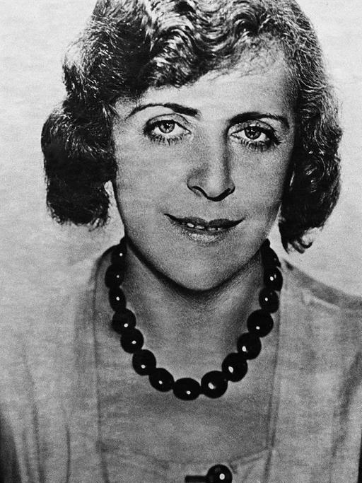 Vicky Baum 1931 in Hollywood, schreibt an einem Tisch mit einer Feder und guckt in Richtung Kamera.