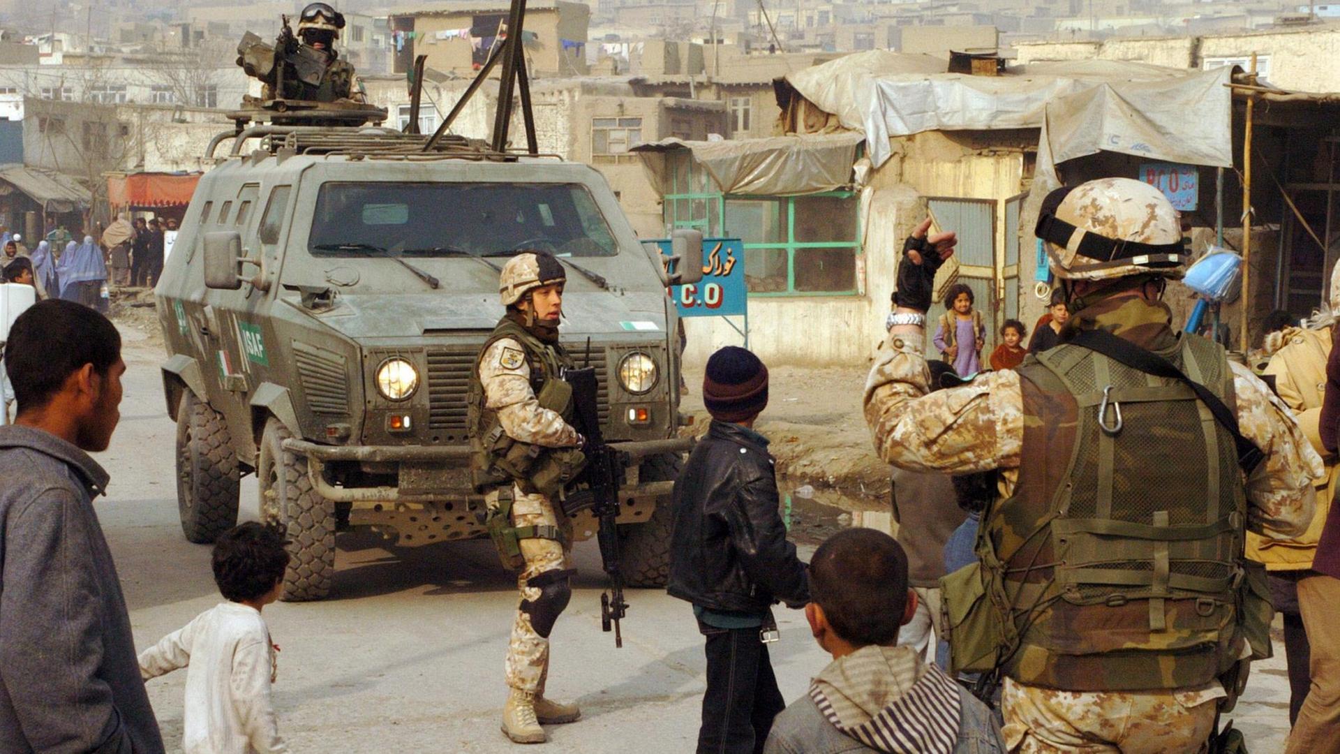 Italienische ISAF-Soldaten bei einer Staßenpatrouille in Kabul. Zwischen den Soldaten laufen Kinder.