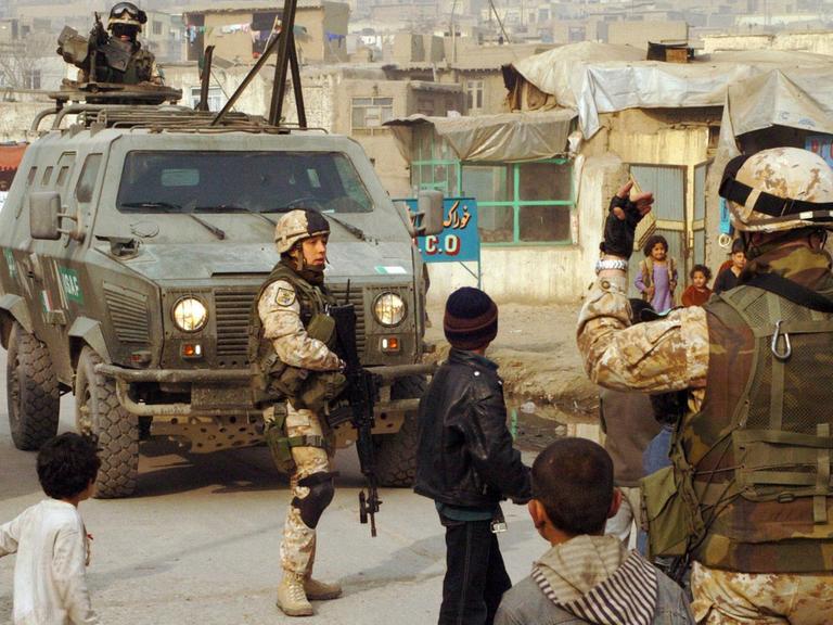 Italienische ISAF-Soldaten bei einer Staßenpatrouille in Kabul. Zwischen den Soldaten laufen Kinder.