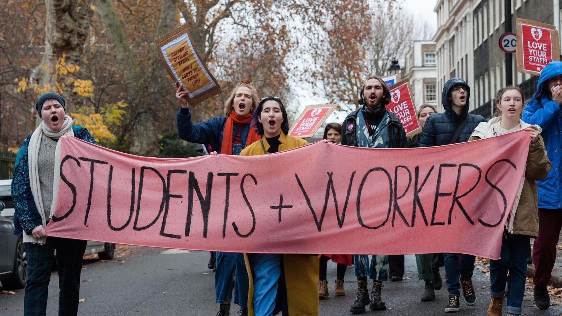 Hochschulmitarbeiter und Studenten laufen am 27. November 2019 mit Bannern an Gebäuden des University College London vorbei. Sie streiken für gerechte Arbeitsbedingungen für Hochschulmitarbeiterinnen und - mitarbeiter.