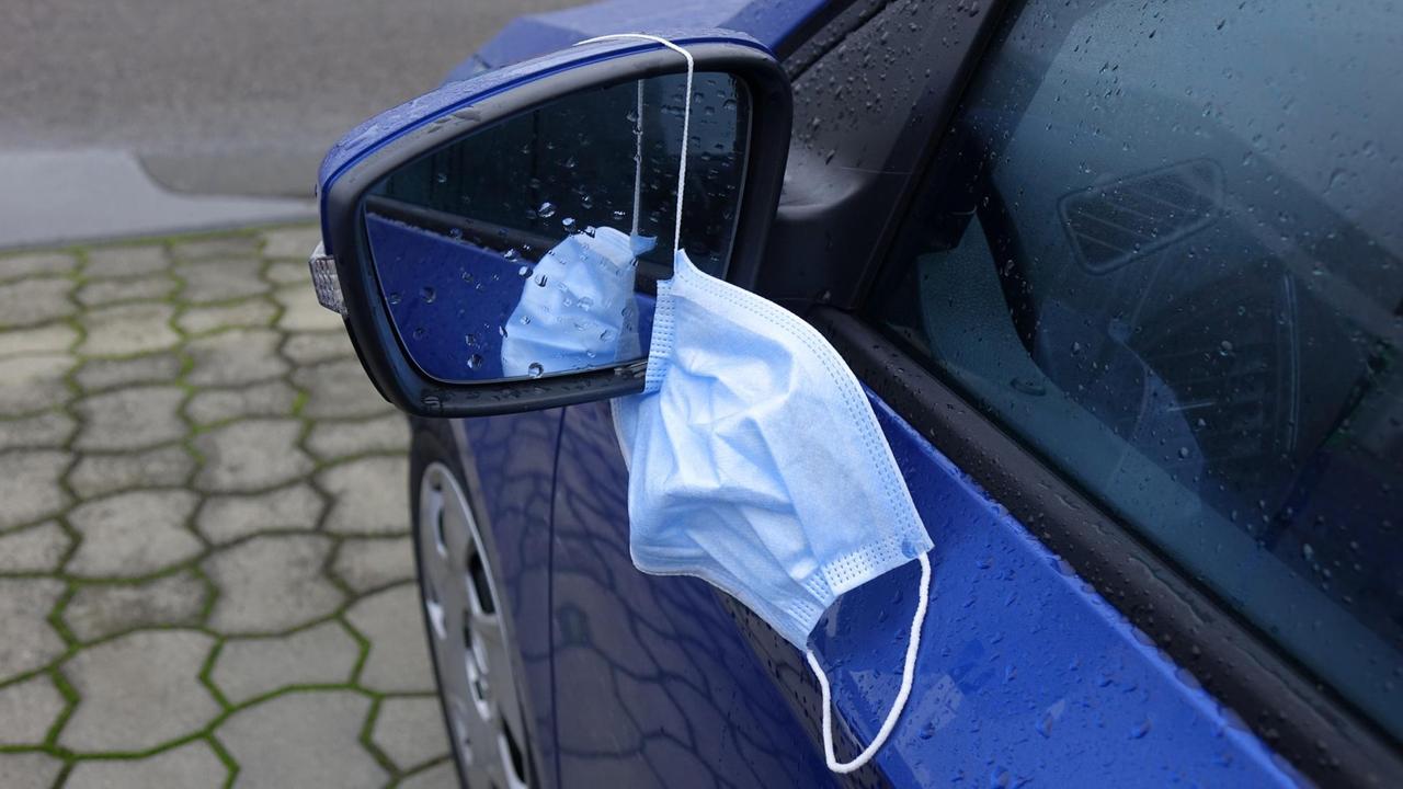 In Borkenwald (Brandenburg) hängt an einem Autospiegel eine Mundschutzmaske.