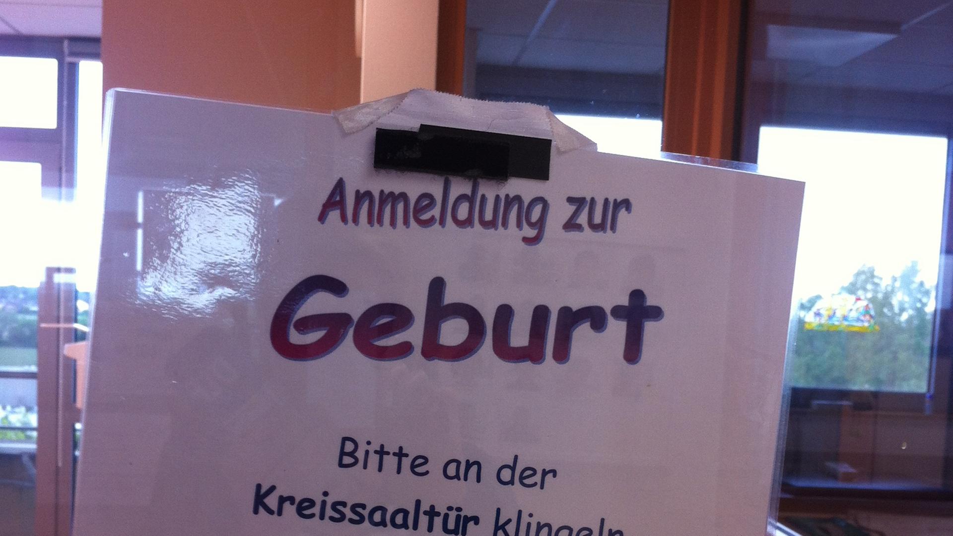 Ein Schild auf dem "Anmeldung zur Geburt Bitte an der Kreissaaltür klingeln" steht.