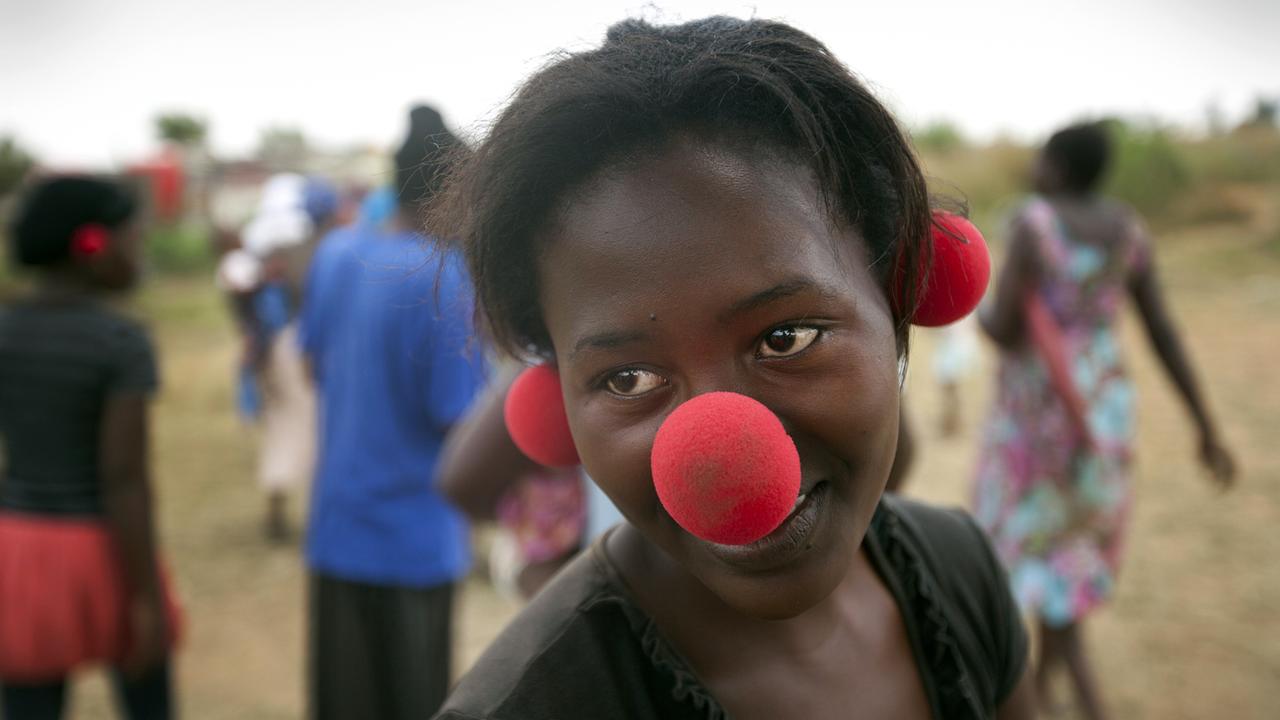 Eine junge Afrikanerin in Johannesburg mit Clownsnase - auf Nase und Ohren -, die sie von der niederländischen Organisation "Africlowns" bekommen hat