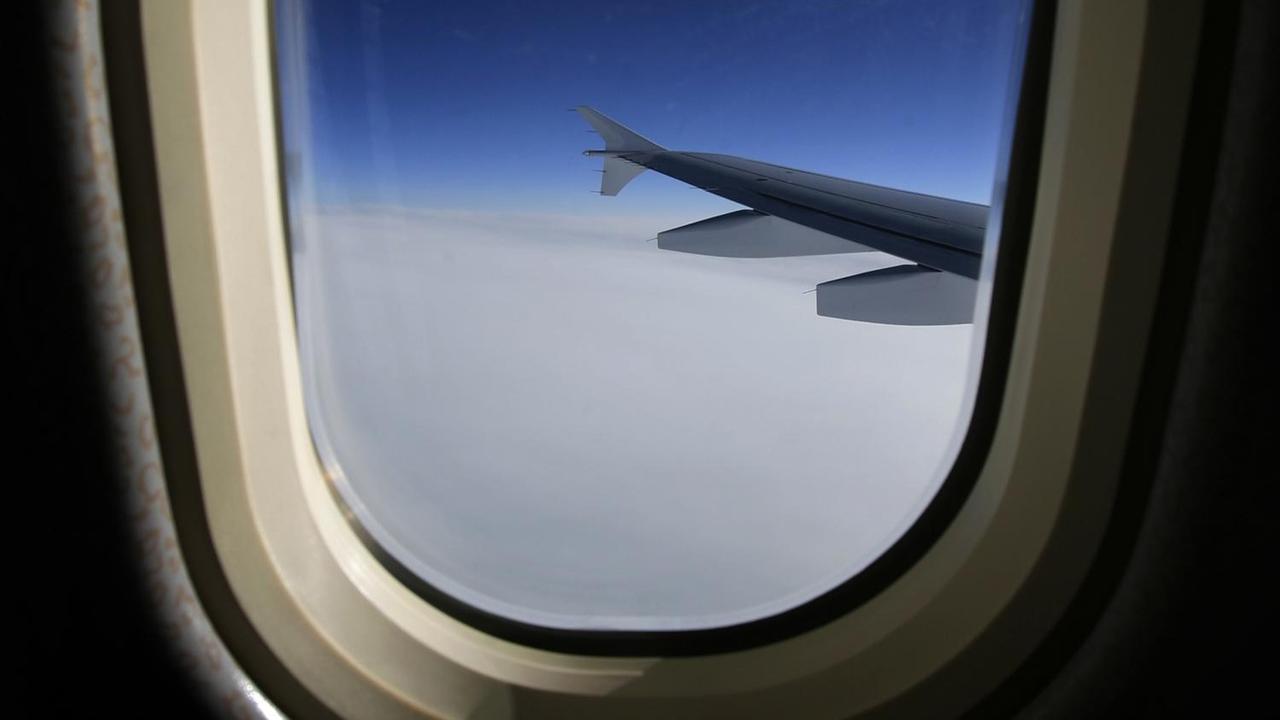 Das Foto zeigt die Tragfläche eines Airbus A310 vor blauem Himmel, aufgenommen in der Luft durch ein Flugzeugfenster.